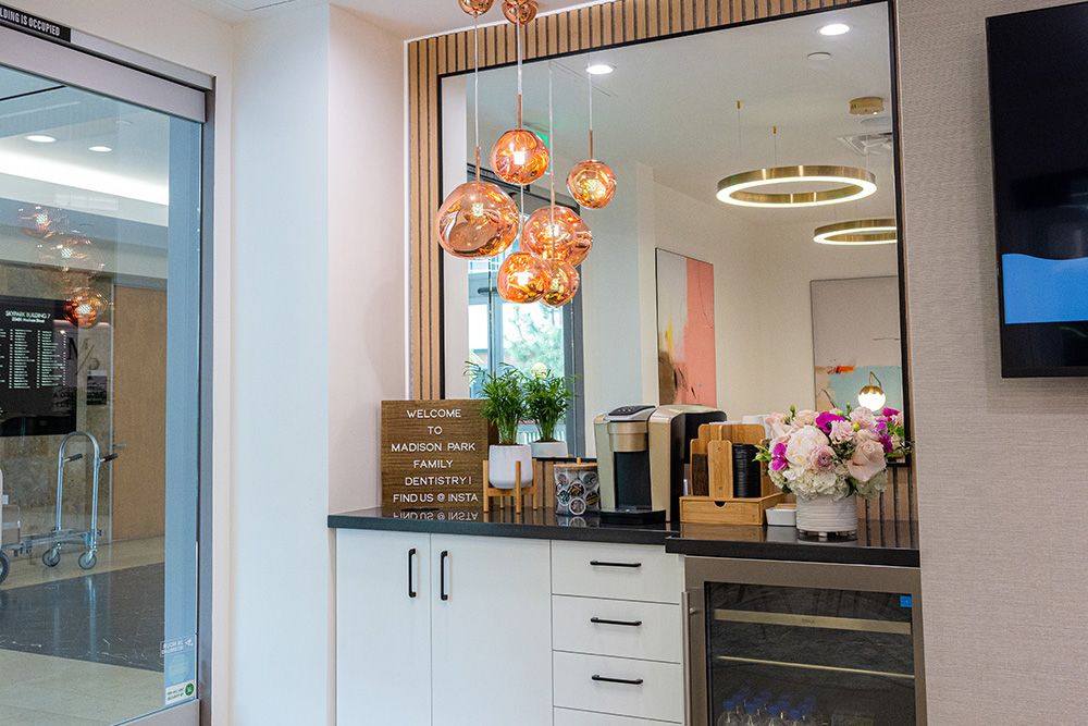 Refreshment station at Madison Park Family Dentistry with drinks, flowers, and welcome sign