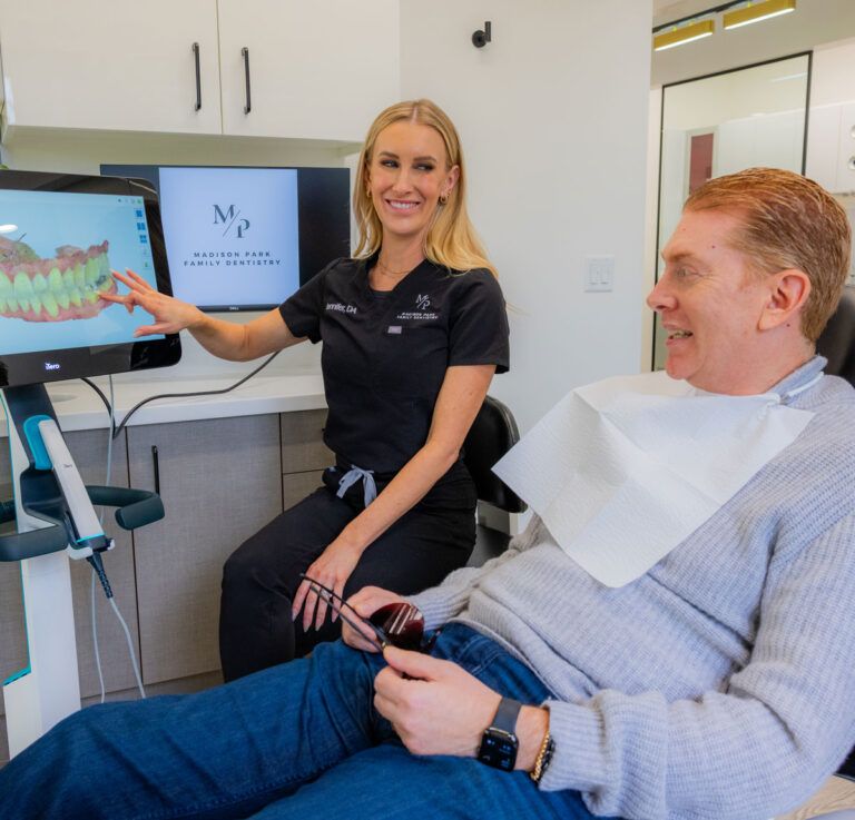 madison-park-family-dentistry-about-our-philosophy-section2 Team member at Madison Park Family Dentistry showing dental scan to smiling patient on screen